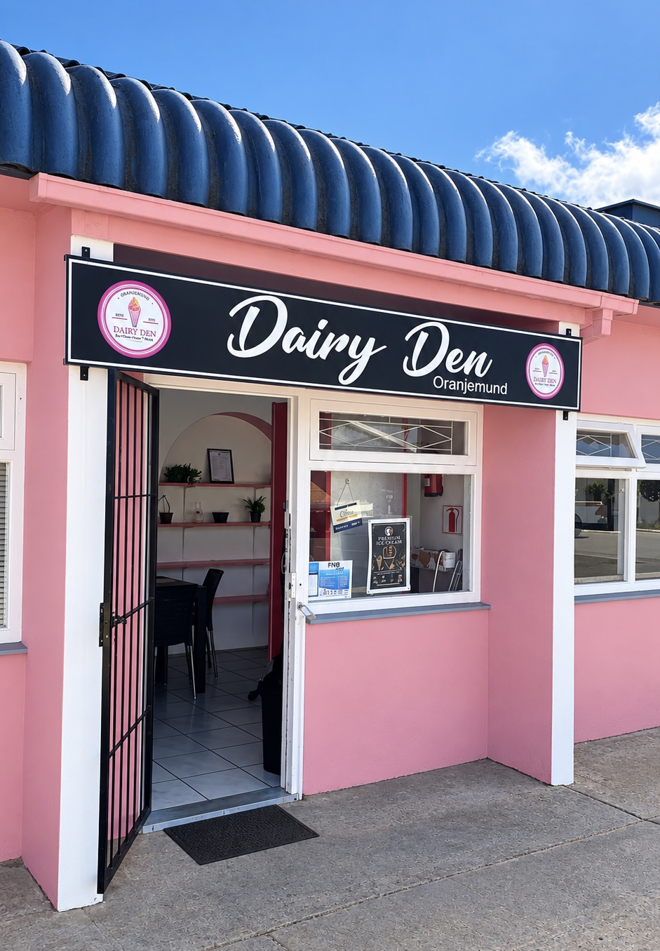 The pink Dairy Den shopfront in Oranjemund with its open door and signage